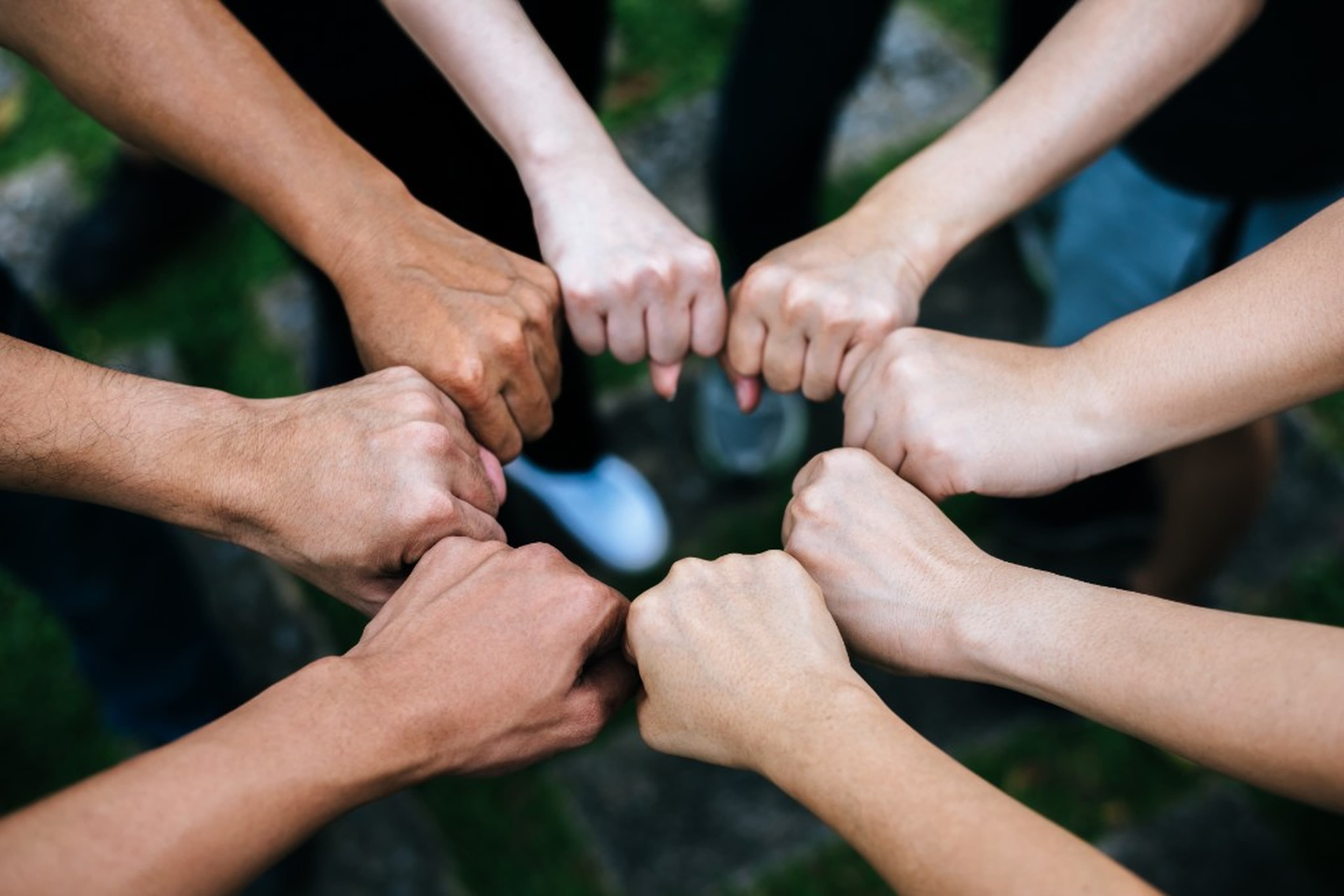 Students joining hands in a fist bump gesture for unity and collaboration